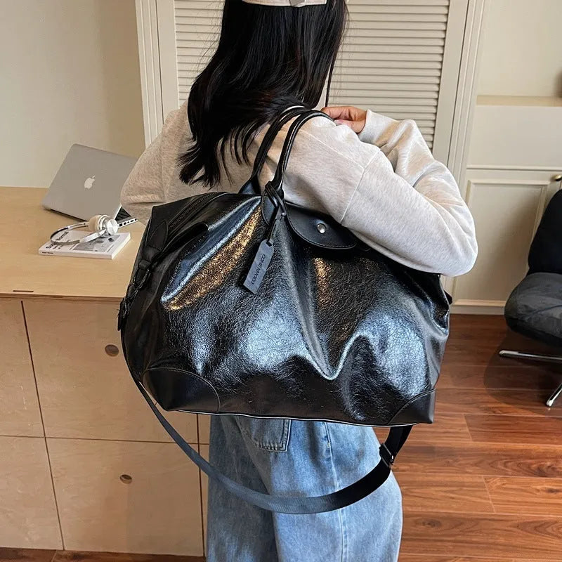 36-55L capacity hand-carry travel bag in black or silver with PU construction and polyester lining