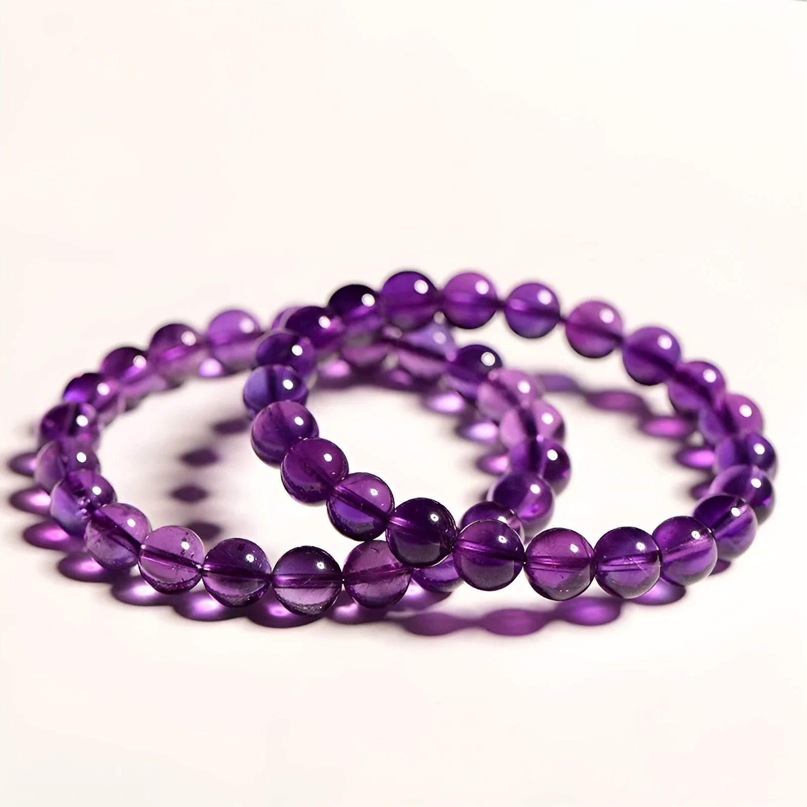 Close-up of a polished natural amethyst bead bracelet with a sliding knot closure on a wrist.