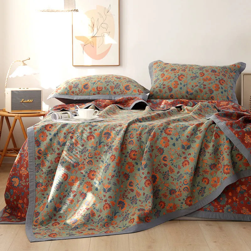 Three-piece cotton gauze bed set with floral plants and flowers pattern, showing blanket and pillowcases.