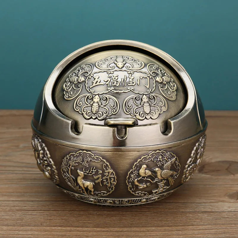 Bronze and red copper alloy decorative ashtray with smoke-extinguishing slot on a table.