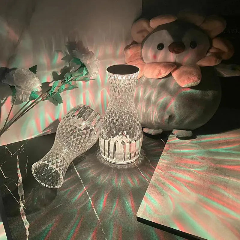 Vase-shaped transparent crystal bedside lamp with touch controls and LED lights on a table.