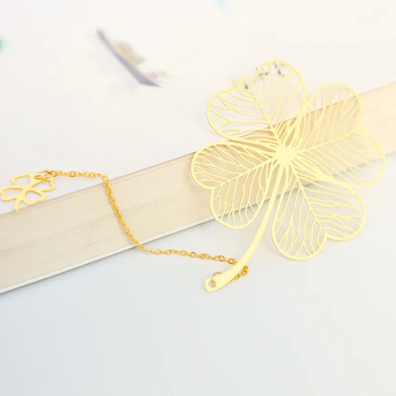 Detailed brass bookmark with hollow maple leaf pendant and rose gold tassel on a book page.