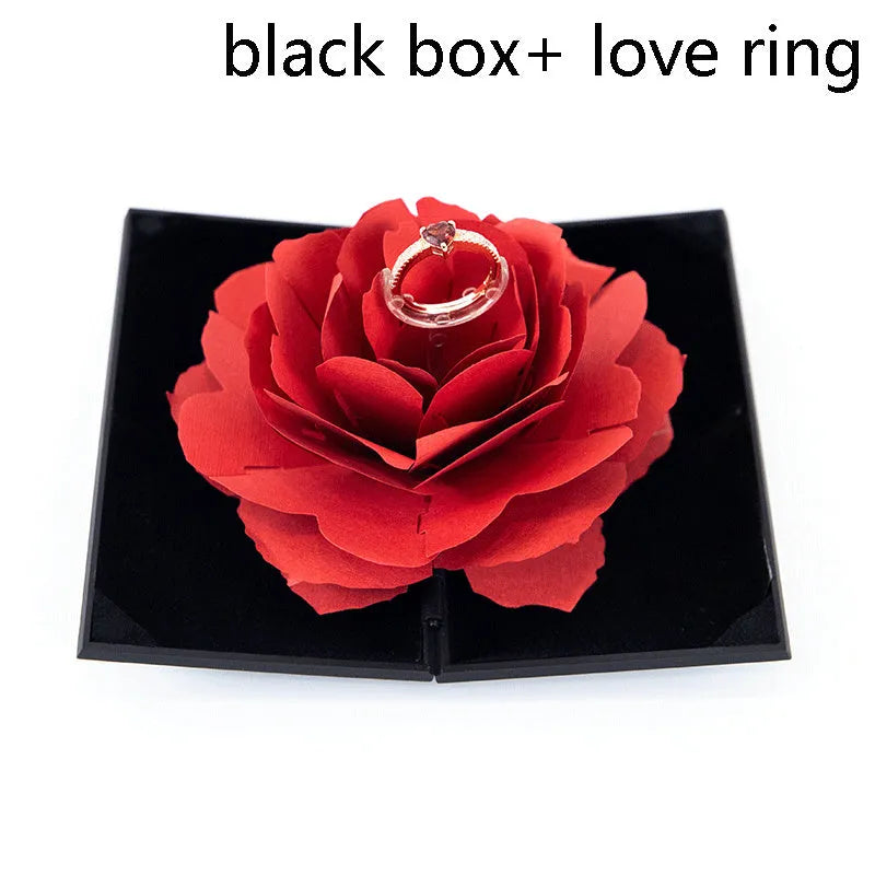 Red heart-shaped rotating ring box with 3D white rose decoration on top.
