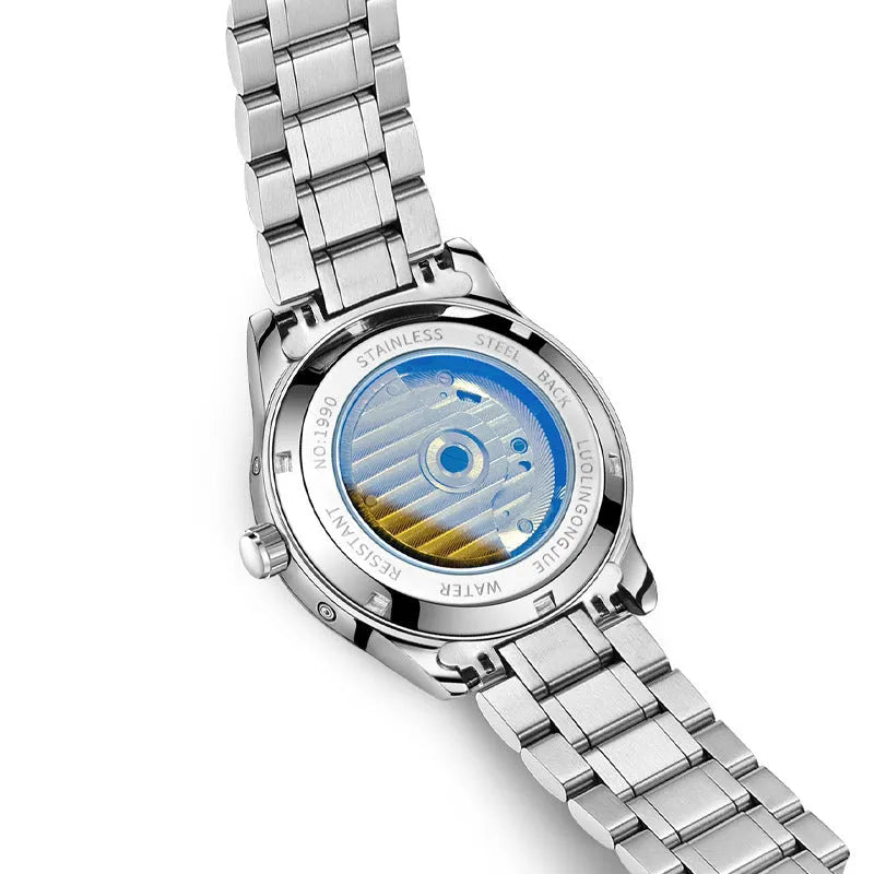 Men's stainless steel mechanical watch with leather strap and butterfly buckle on a business suit cuff.