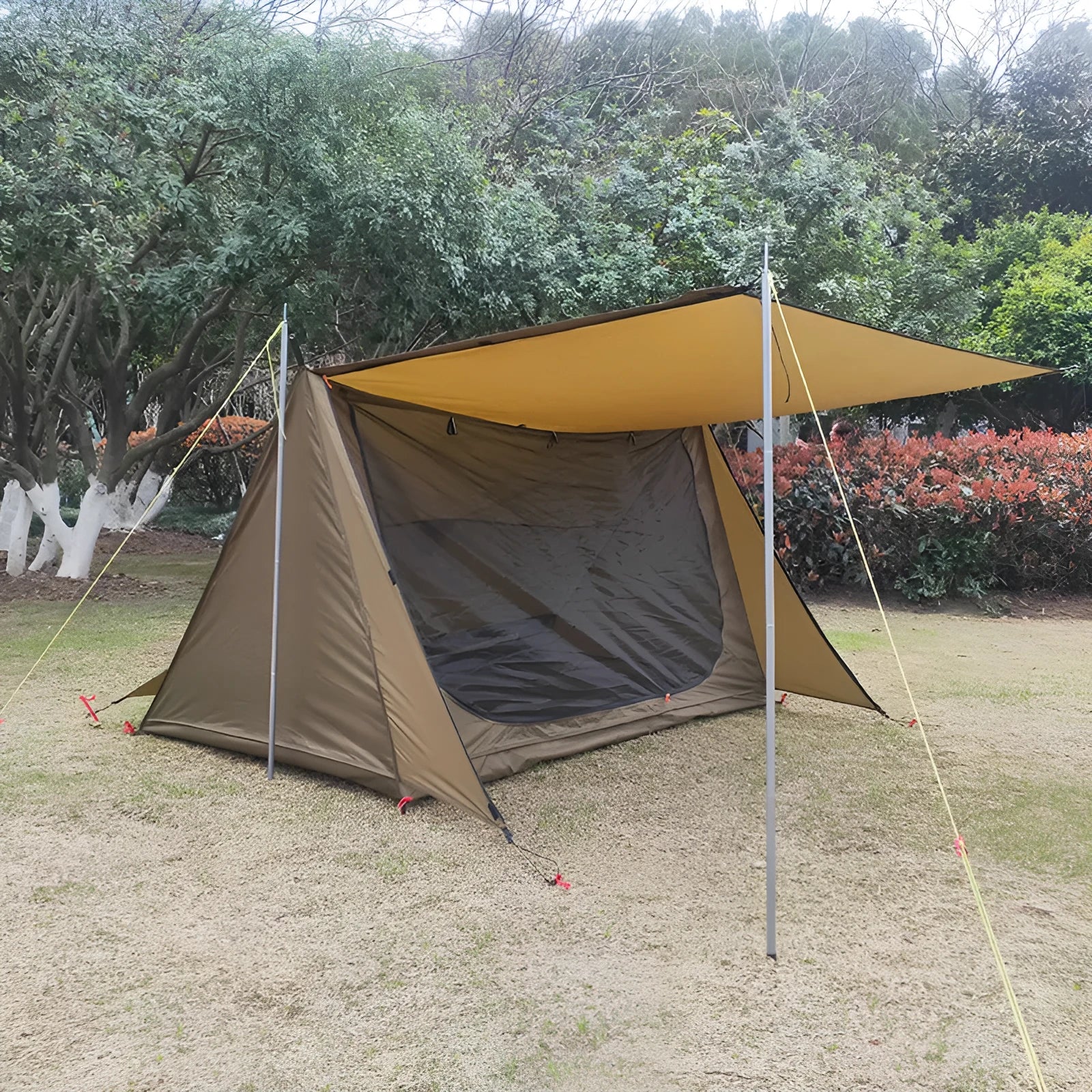 Brown shelter tent for two people with two aluminium alloy poles set up on grass