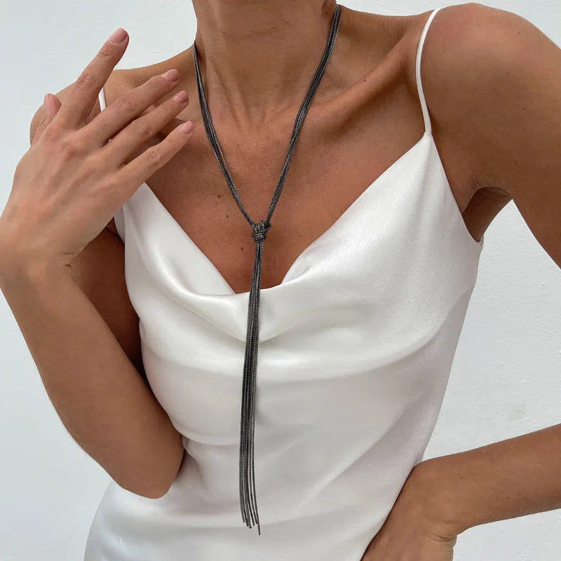Simple Y-shaped metal tassel necklace set with gold finish and matching earrings on white background