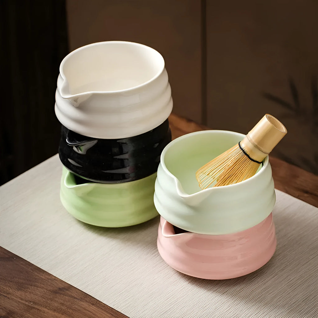 Ceramic matte tea whisk stand in bright white holding a bamboo matcha whisk upright on a wooden tray