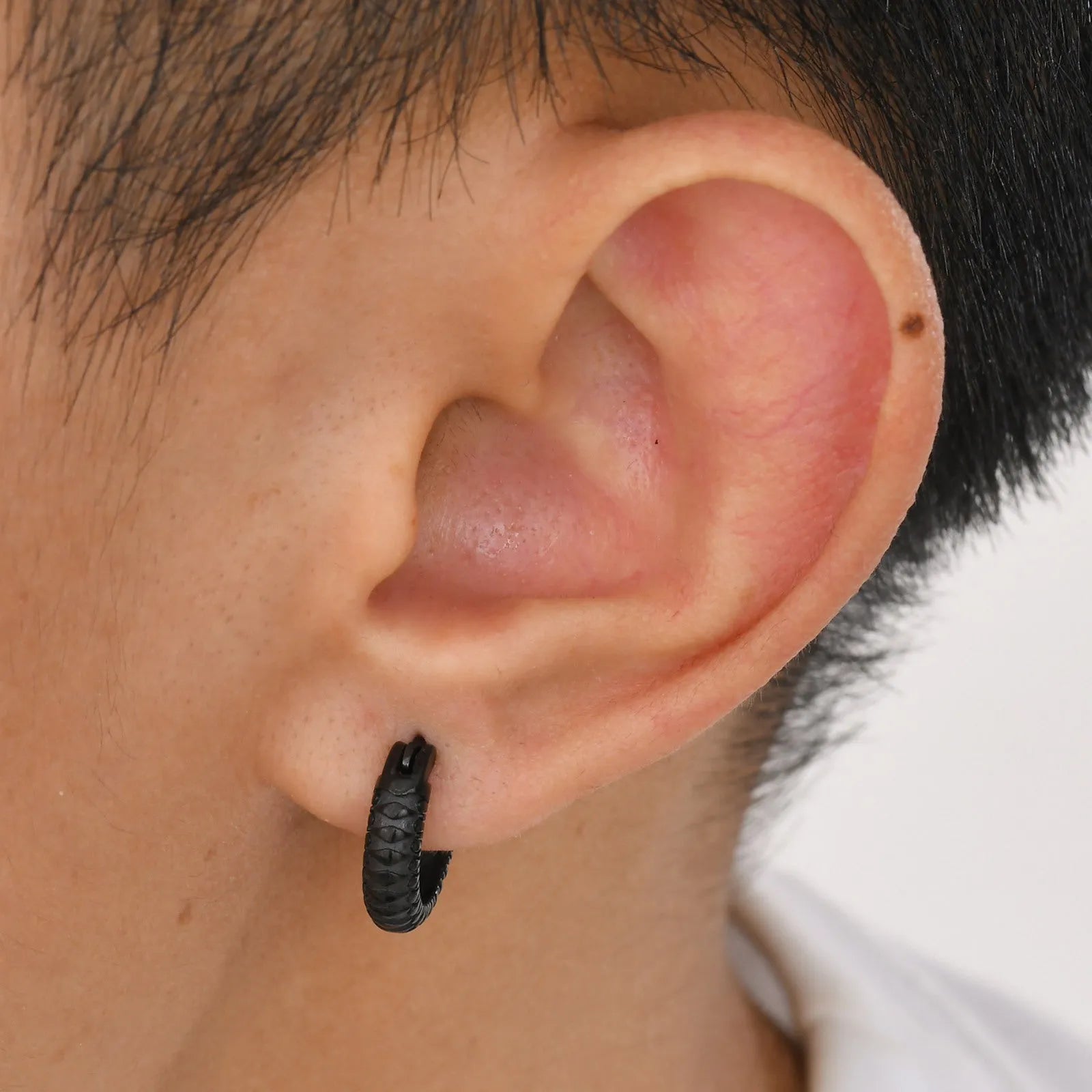 A pair of stainless steel stud earrings for men with a snake pattern, shown in black and gold colour options.