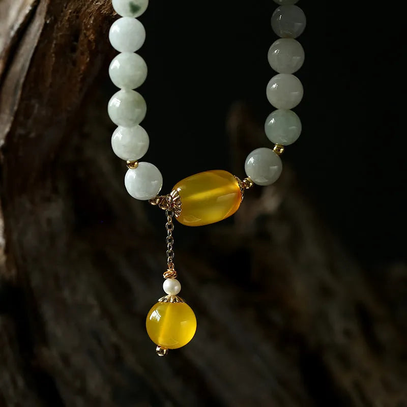 Women's ethnic bracelet with hanging red agate tassel on a gold chain.