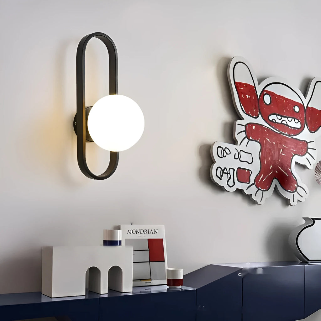 Modern minimalist wall lamp with black iron arm and clear glass shade, mounted on a plain wall.