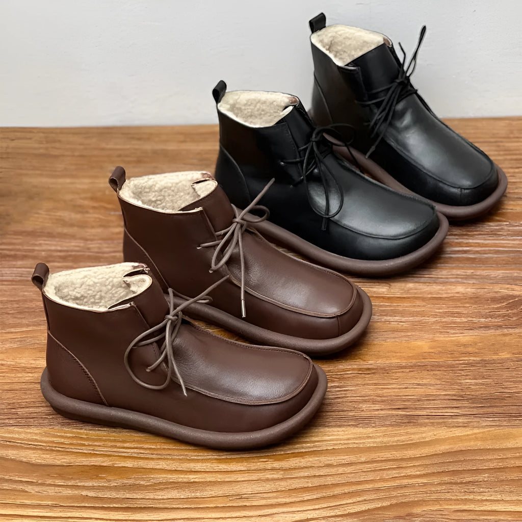 Women's black cowhide ankle boots with flat heel and round toe on a plain background