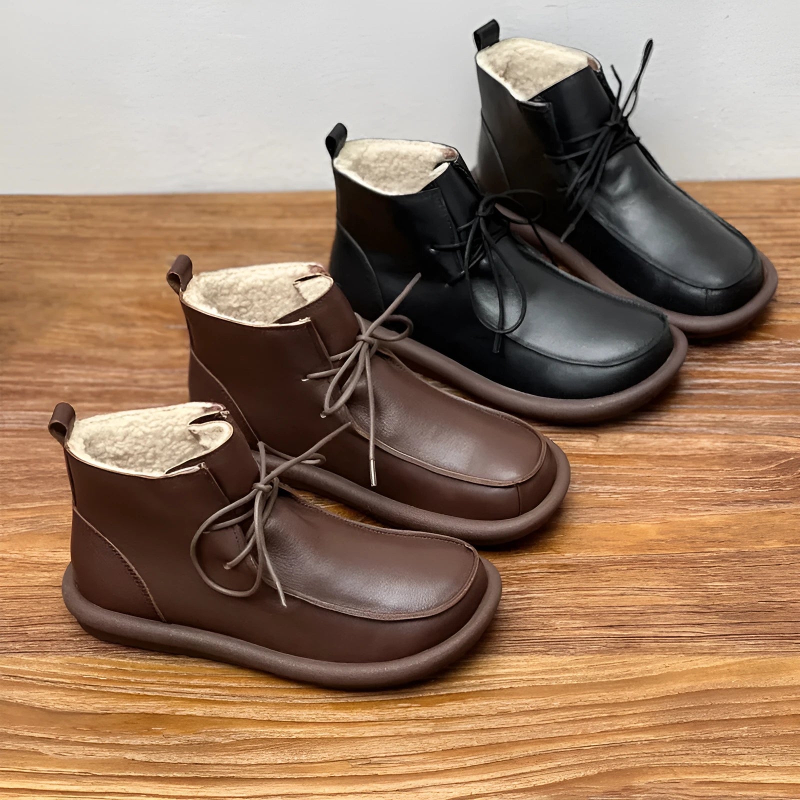 Women's black cowhide ankle boots with flat heel and round toe on a plain background