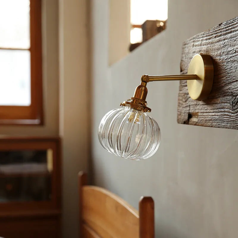 Creative pumpkin-shaped wall lamp with a textured glass shade mounted on a white wall.