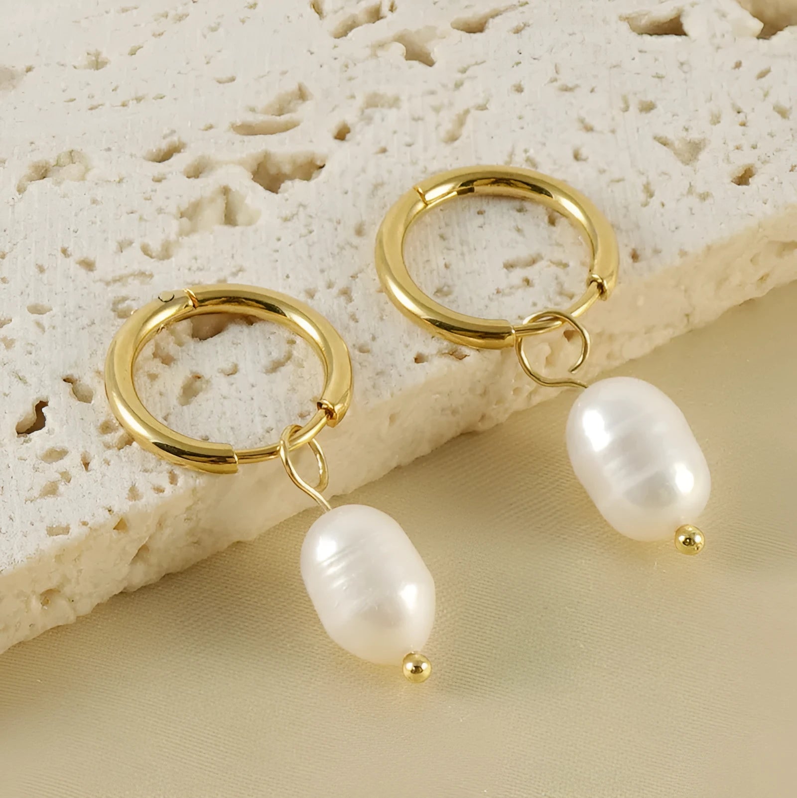 A pair of gold geometric-shaped stainless steel earrings featuring a central pearl and titanium steel posts.