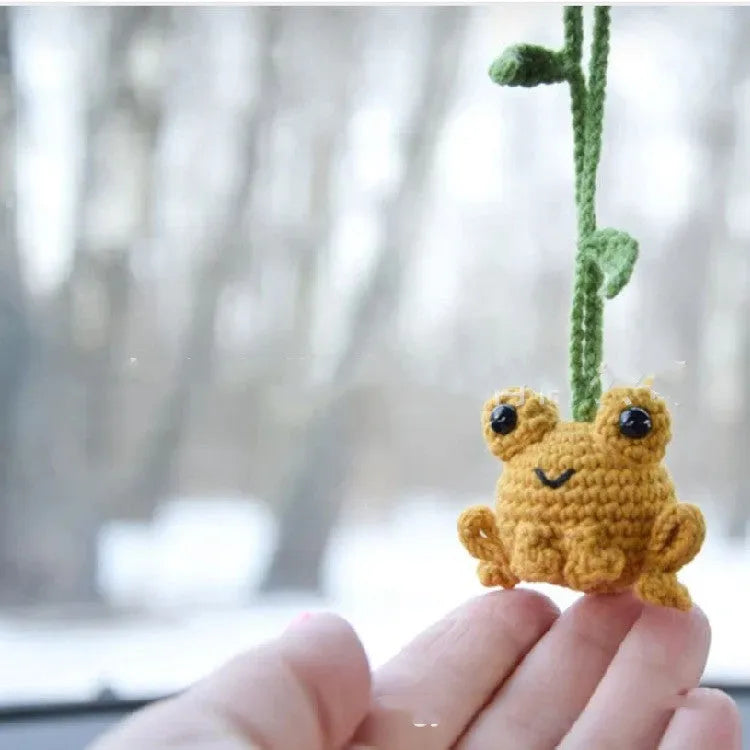 Handmade green plush frog car pendant hanging, showing woven cord and cartoon style.