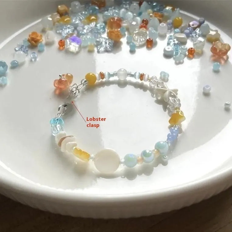 Orange mixed material women's bracelet with diamond shape and round decorative seaside elements.