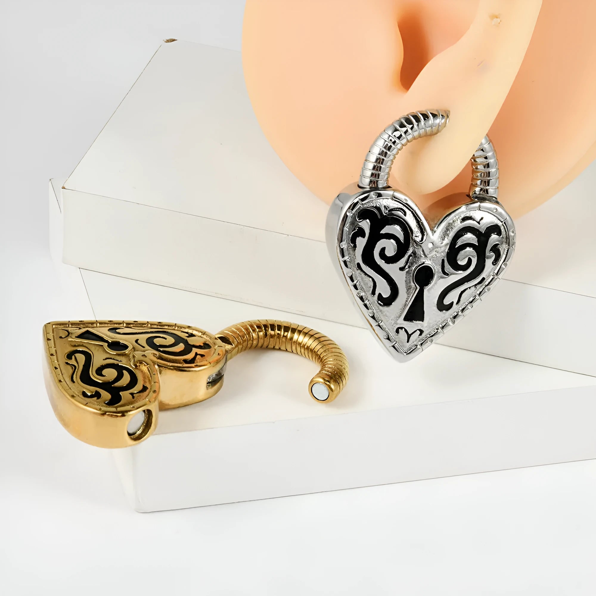 Heart-shaped stainless steel ear piercings in gold and steel colour options showing front and back views