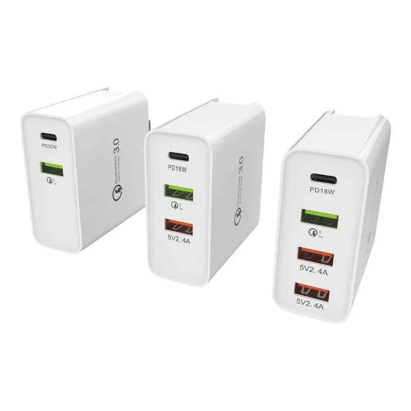 White multi-port fast charge wall charger with UK plug on a table.