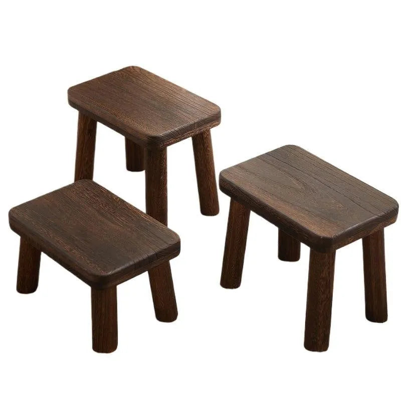 Distressed solid wood shoe changing stool with rustic bracket structure.