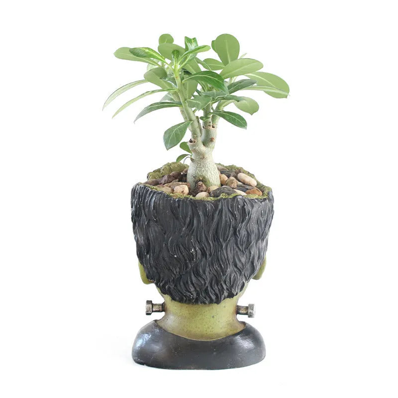 Green Man resin flower pot with sculptural relief detail on white desktop