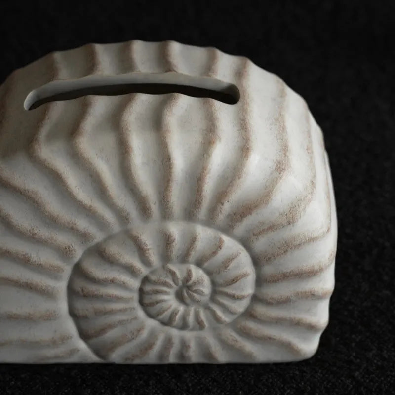 White conch ramble shell design resin tissue box holder on a table.