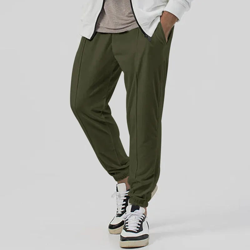 Man wearing grey straight-leg tapered sweatpants, showcasing the mid-rise waist and casual fit.