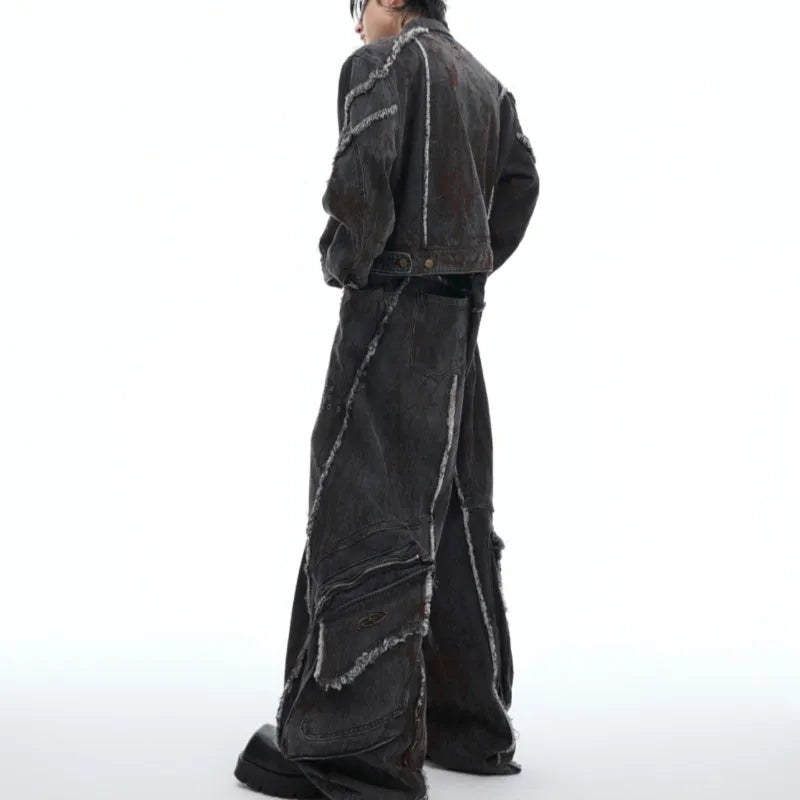 Black raw-edge splash-dye distressed denim coat with padded shoulders and matching trousers on a hanger.