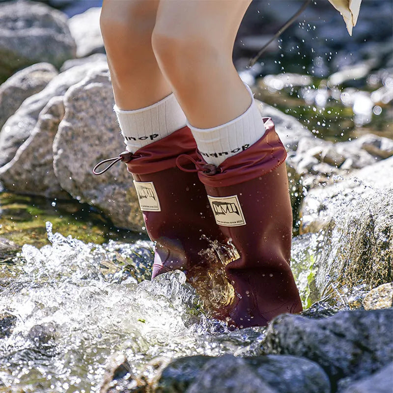 A pair of high tube PVC rain boots in a solid colour, shown on a size label with a non-slip sole.