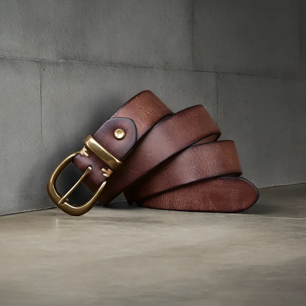 Men's brown leather belt with copper pin buckle on a flat surface