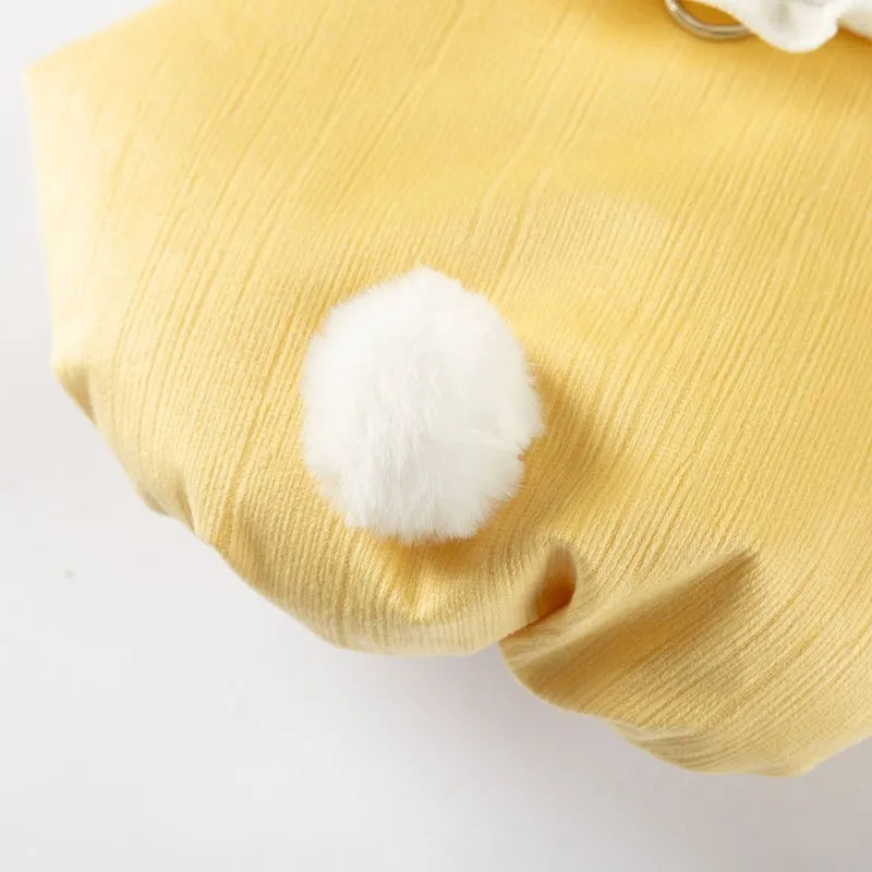 Small dog wearing a lavender bunny embroidered pet coat with white ruffled collar and fluffy pom-pom tail
