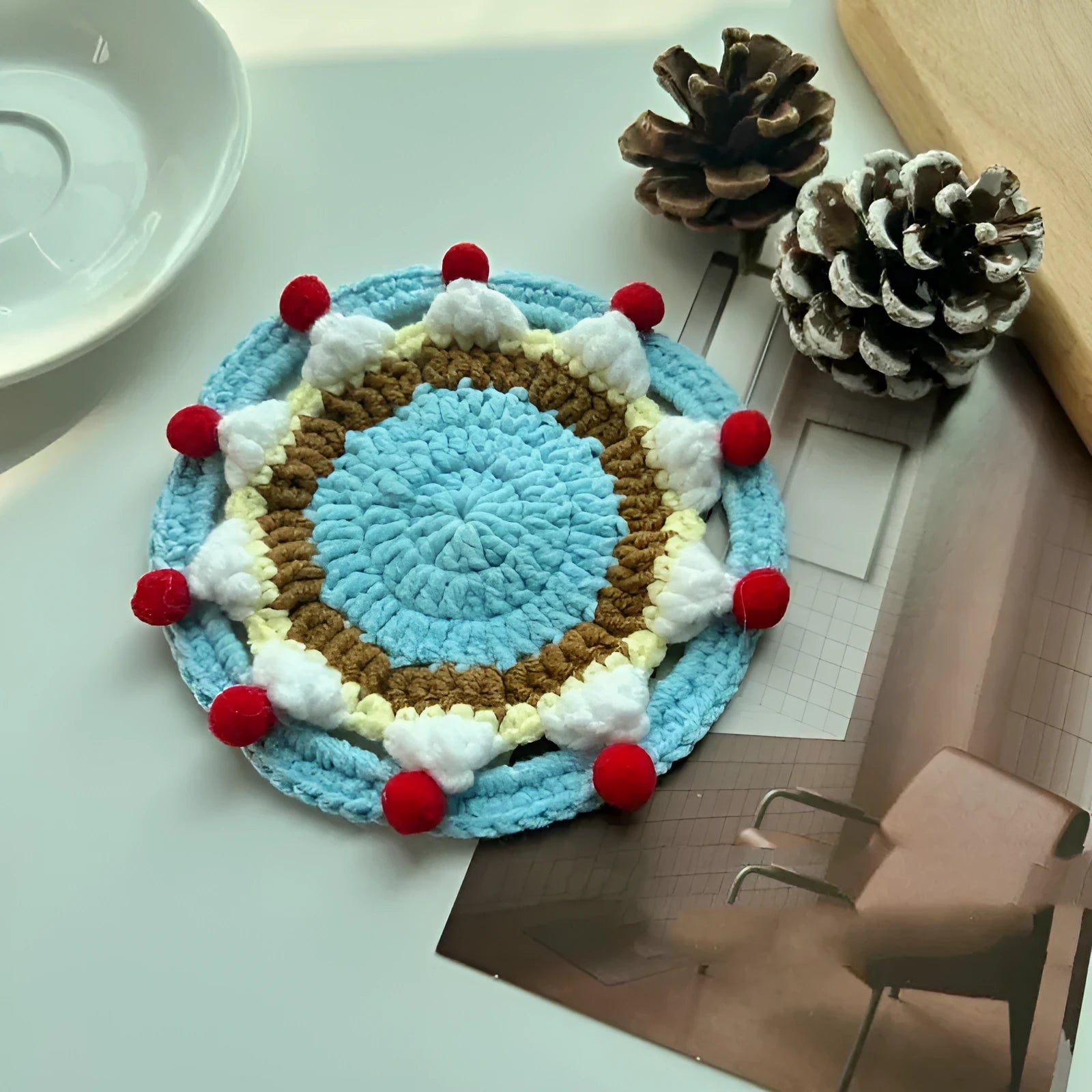 Circular wool felt coaster with cake design, 9 cm in diameter, shown on a table.
