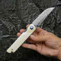 Damascus steel folding knife with black finish and ox bone handle, blade open showing 8.5cm cutting edge