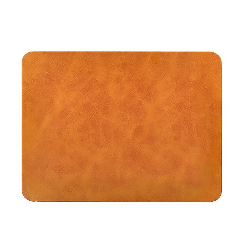 Brown leather wireless charging mouse pad on a wooden desk with a smartphone charging on its surface.