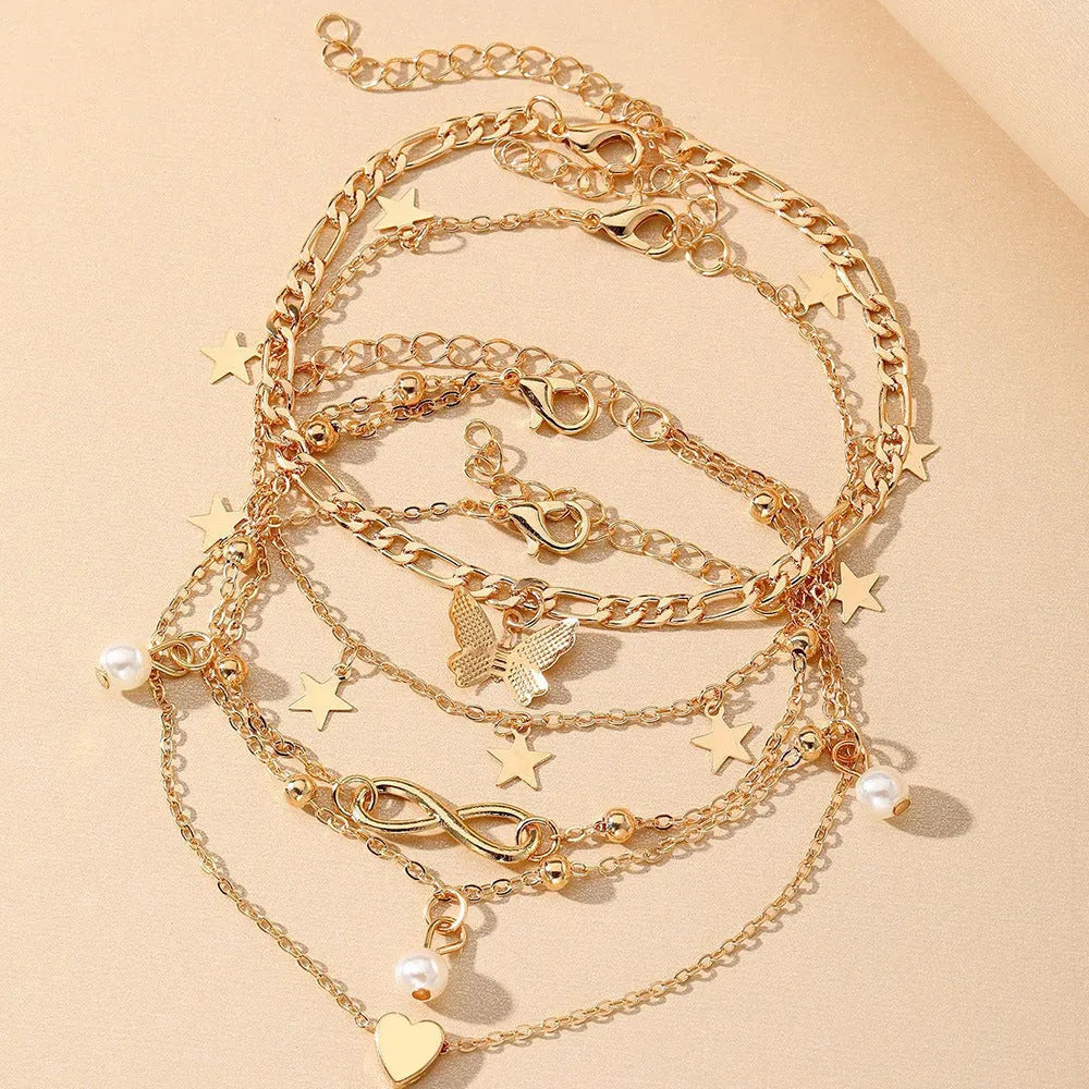 Set of four women's alloy anklets with butterfly and pearl heart designs arranged together