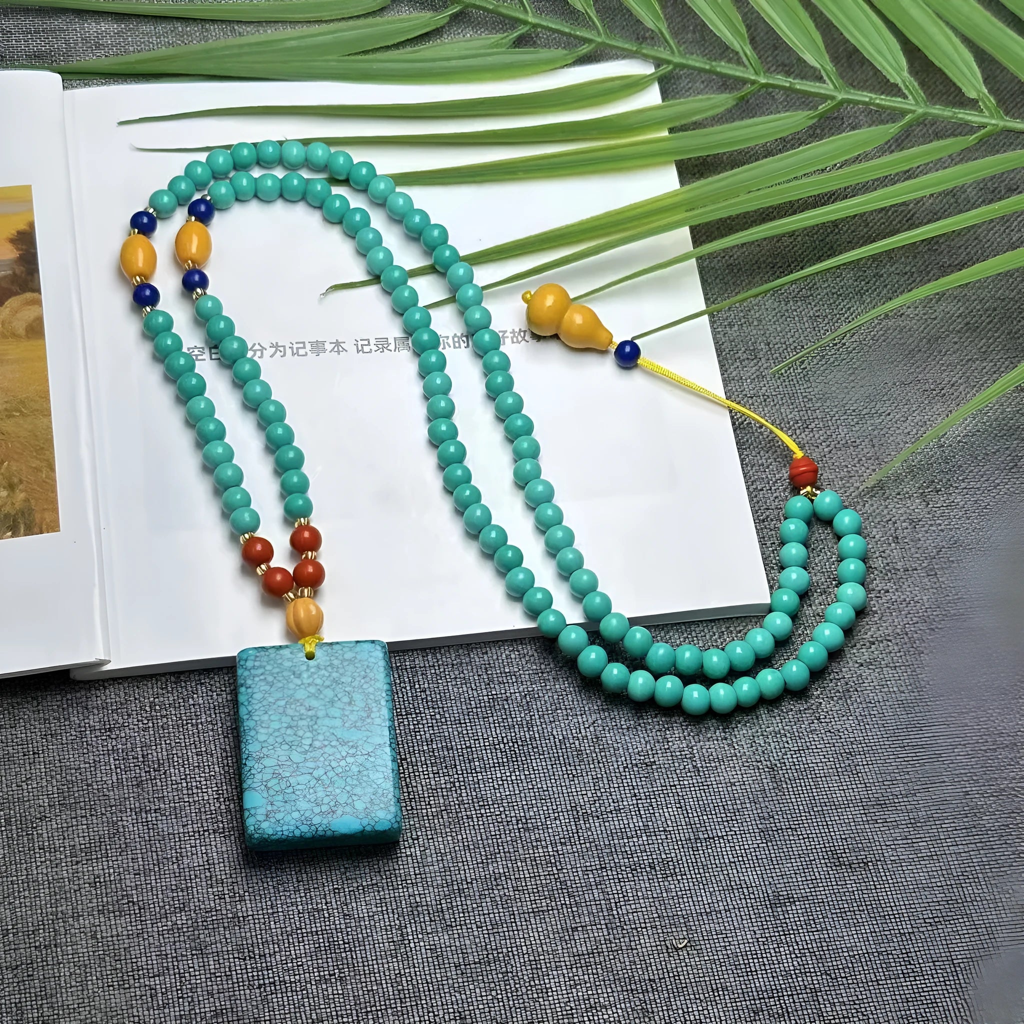 Turquoise mesh flower lucky pendant on a ball bead chain necklace, showing clasp.