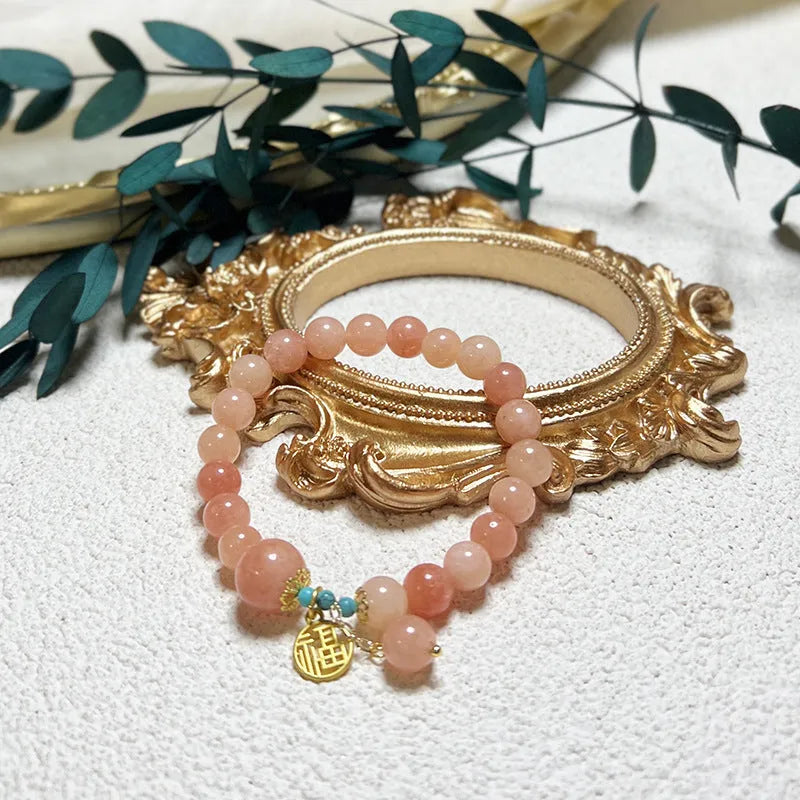Pink alloy bracelet with natural stone details for women on a simple background.