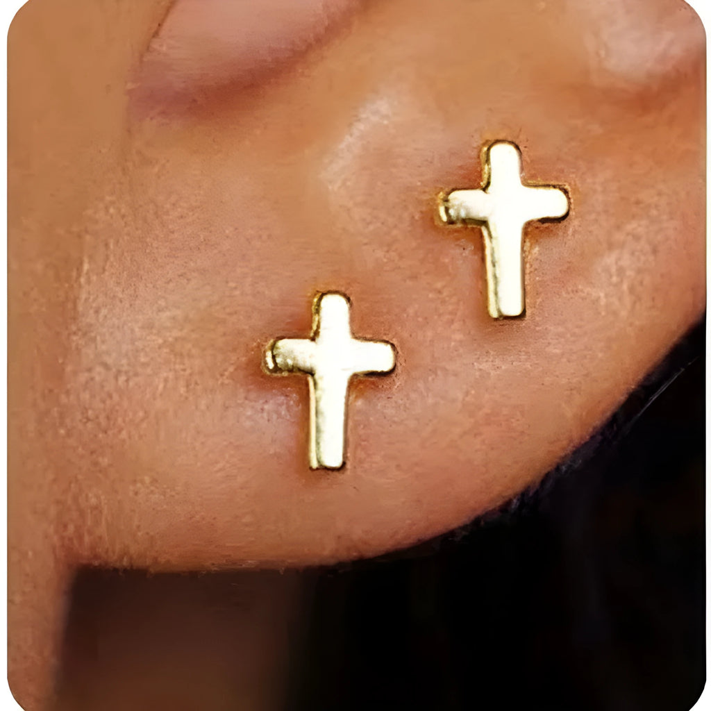 Women's gold bow stud earrings and silver cross stud earrings on a flat surface.