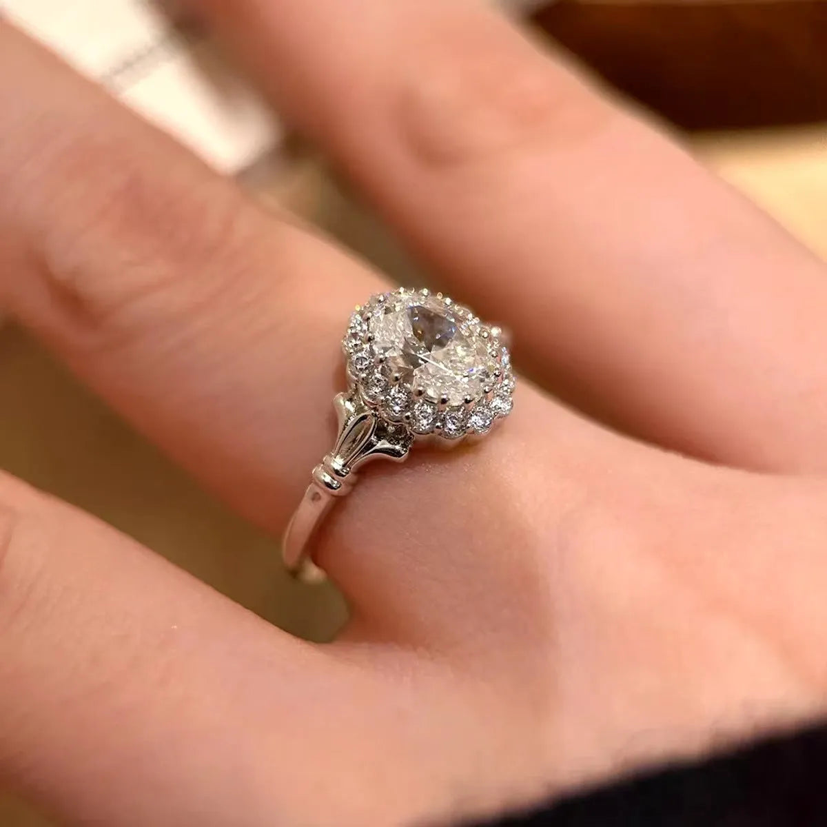 Close-up of a silver geometric ring with a large elliptical diamond on an adjustable open band.