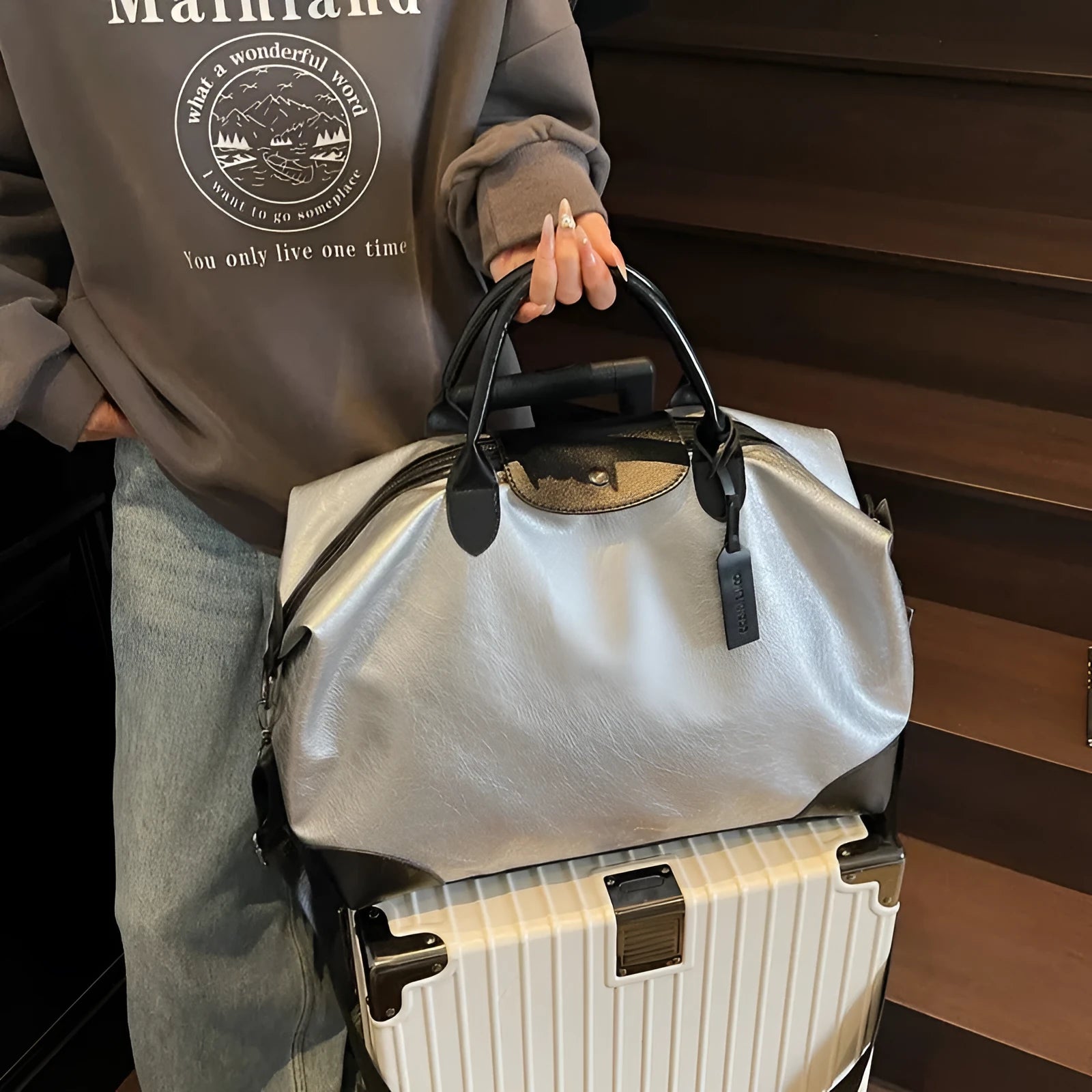 36-55L capacity hand-carry travel bag in black or silver with PU construction and polyester lining