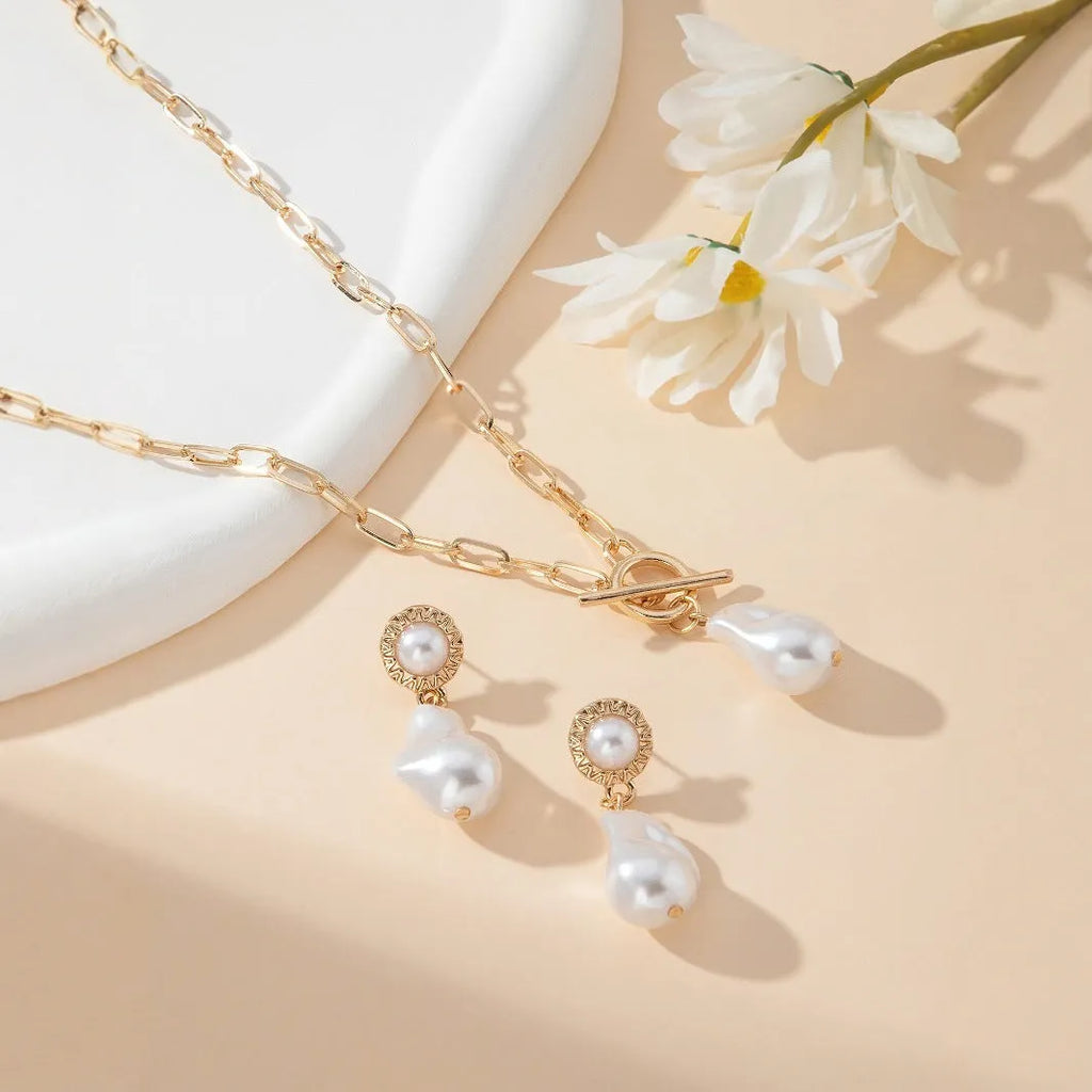 Gold baroque pearl pendant necklace and matching ear stud jewellery set on white background