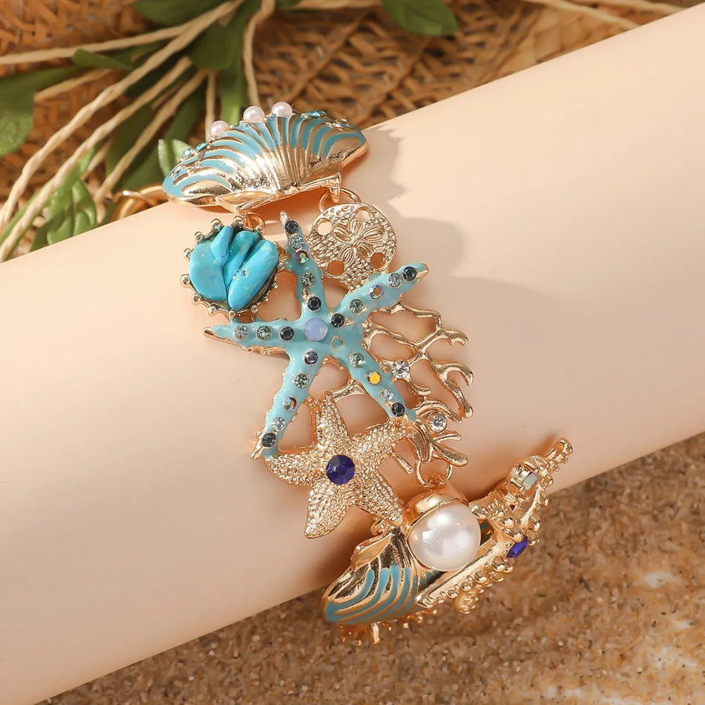Alloy rhinestone bracelet with boat anchor, shell, and starfish charms in turquoise, red, or blue.