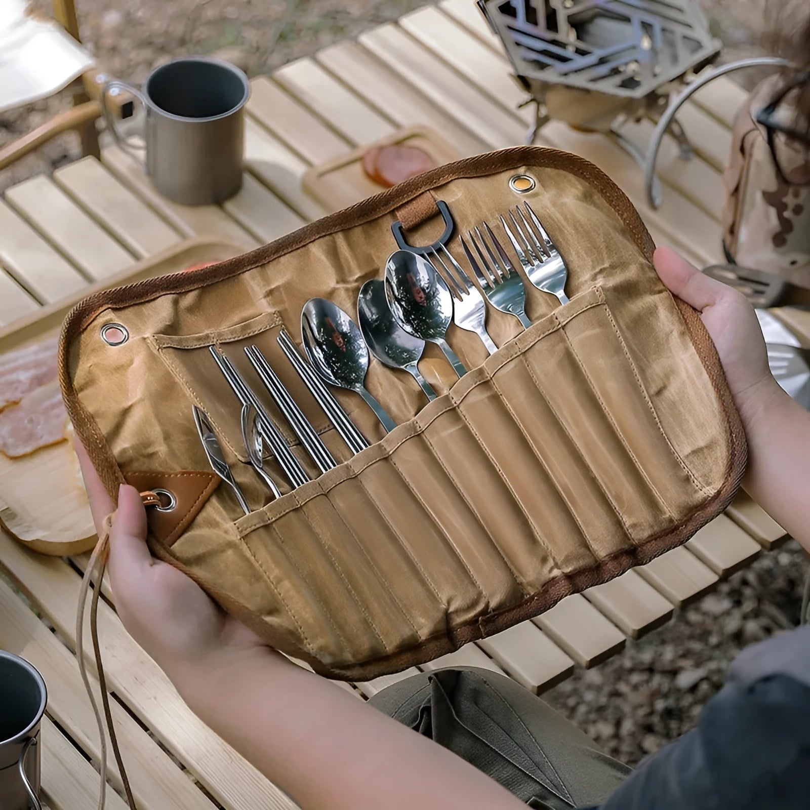 Waxed canvas tableware storage bag open to show wooden handle knife, fork, spoon, butter knife, and chopsticks.