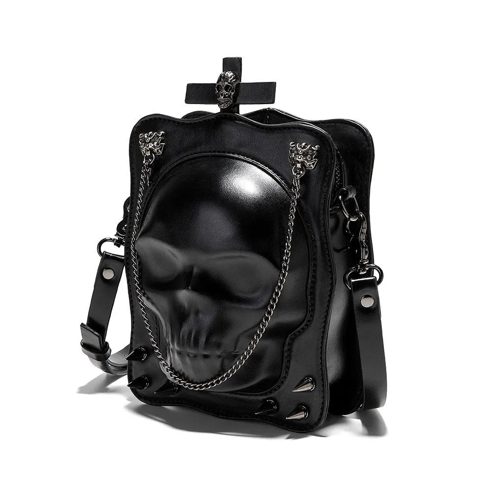 Black mini square crossbody bag with embossed skull design, metal chain strap, and zip closure.