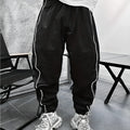 Man wearing loose-fit cropped sports trousers in bamboo fibre, showing army green colour and elastic waist.