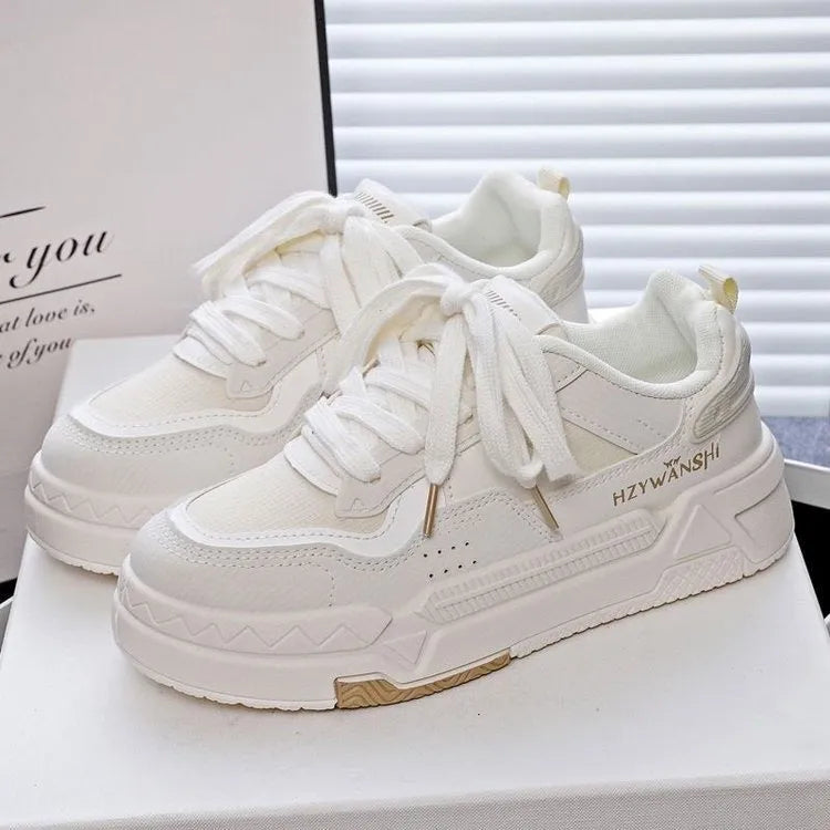 Beige children's platform trainers with cross shoulder straps and white laces on a 3cm thick rubber sole.