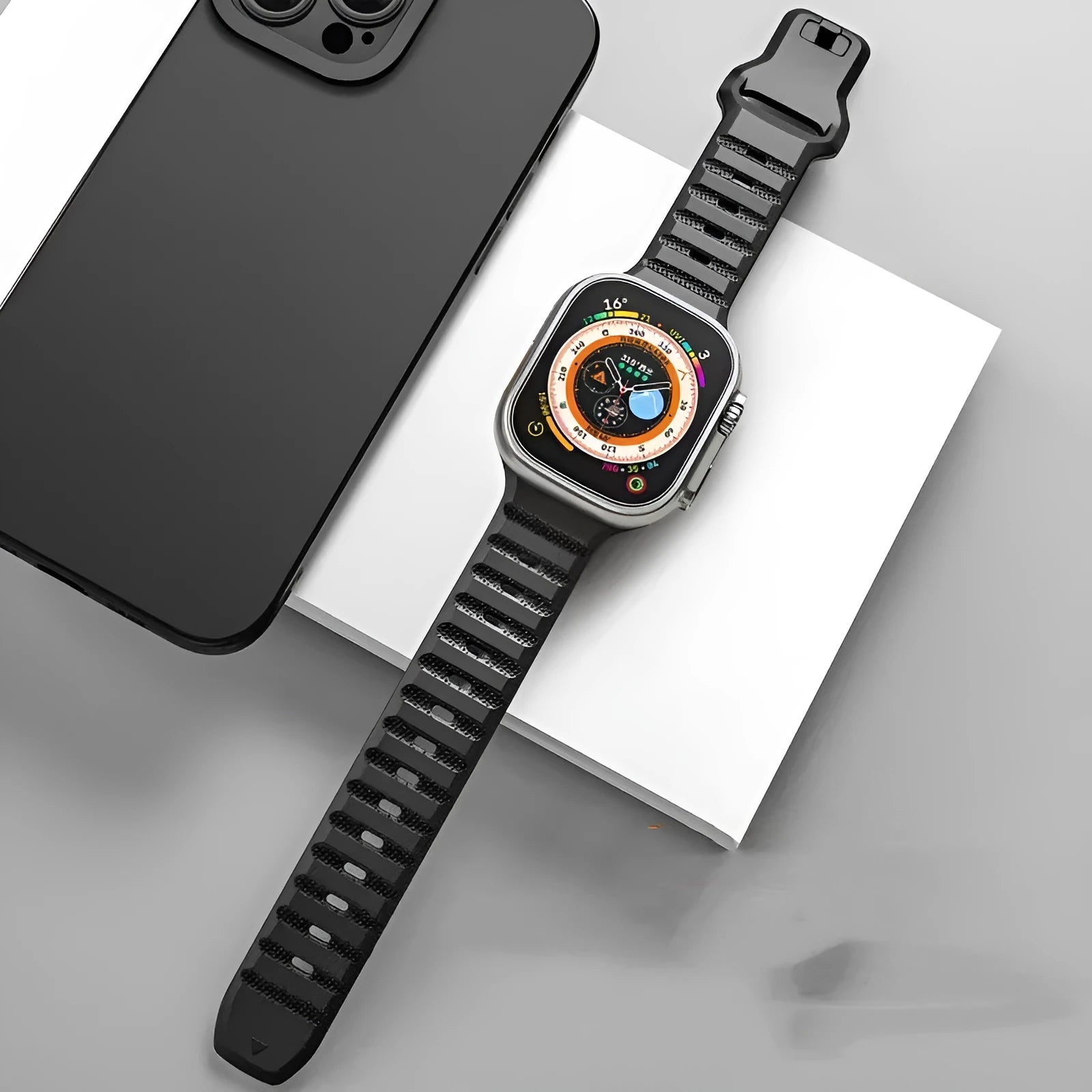 Black fluoro rubber Apple Watch band with T-buckle closure on a wrist, showing compatible Ultra model.