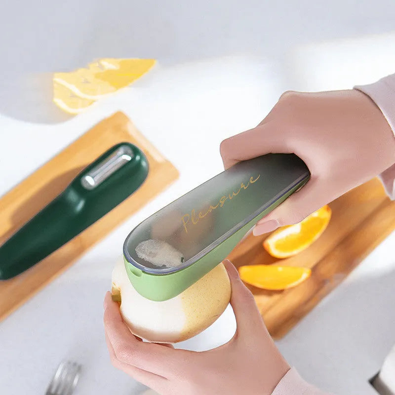 Dark green kitchen peeler with storage tube and stainless steel blade on a kitchen counter.