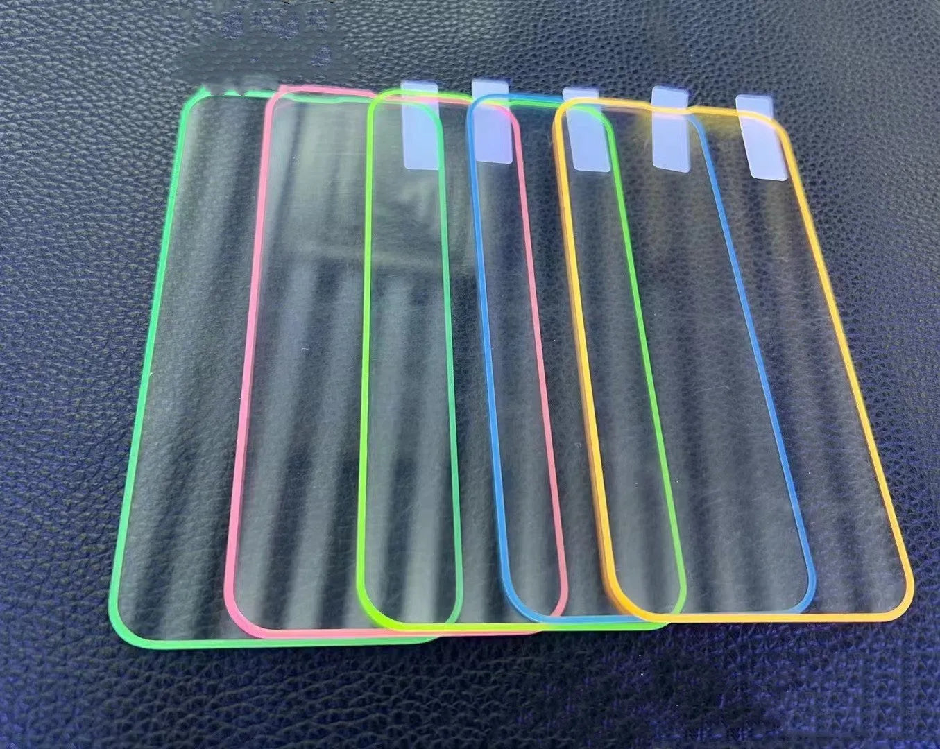 Fluorescent tempered glass screen protector for iPhone with glowing green edge on a phone