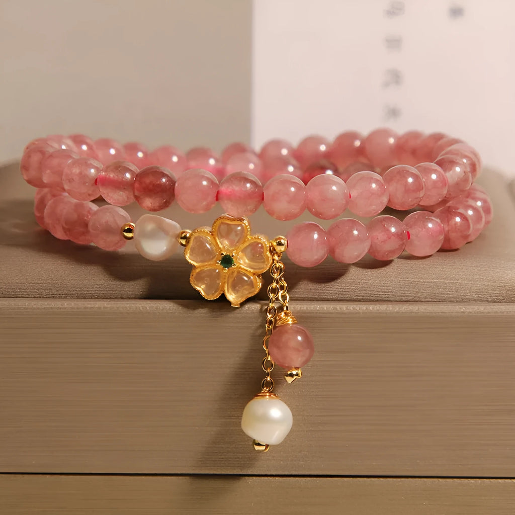 Women's double ring bracelet with strawberry quartz four-leaf clover charms on wrist.