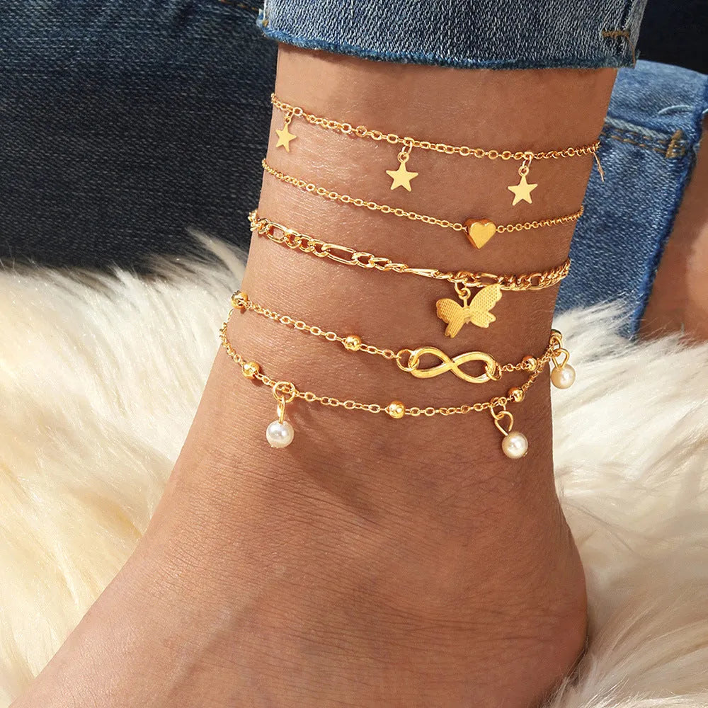 Set of four women's alloy anklets with butterfly and pearl heart designs arranged together